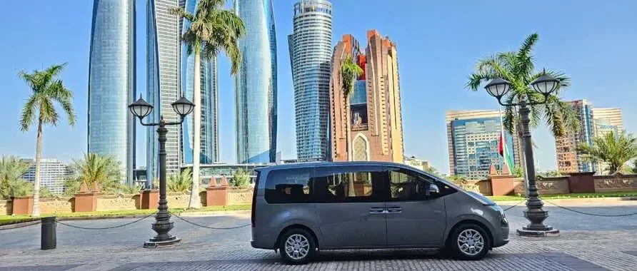 A small Hyundai Staria 2.2 parked outside a tall building, available for rentals in Dubai.