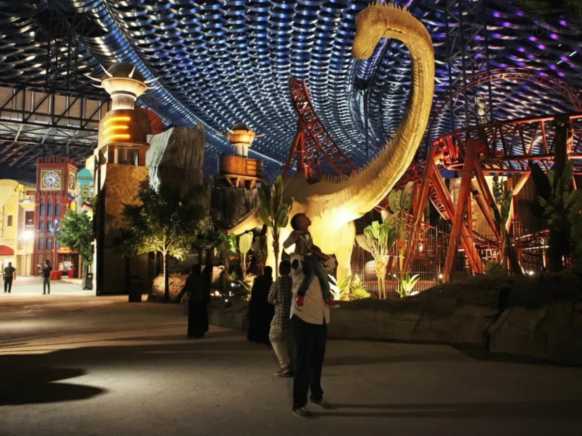A family looking at a giant life-sized dinosaur in the Lost Valley zone at IMG Worlds of Adventure Dubai United Arab Emirates.