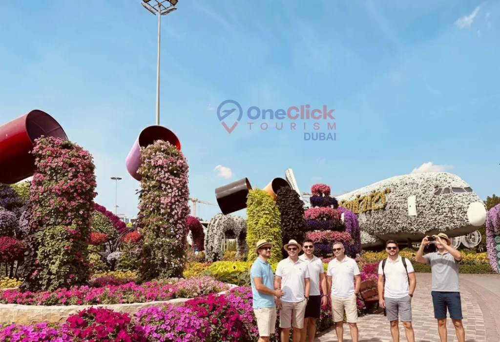 Male tourists posing in front of the flower-covered Emirates A380 at Miracle Garden Dubai.