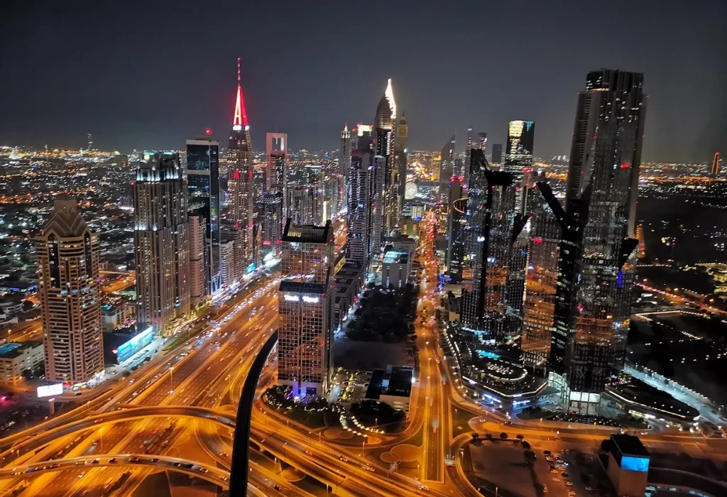 High-angle panoramic night view of the illuminated Sheikh Zayed Road and Dubai city skyline from the Sky View Hotel Dubai.