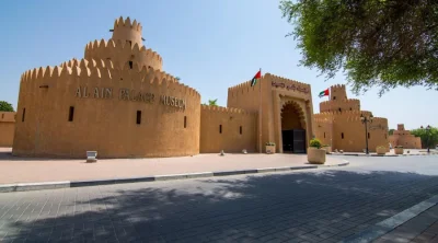 Exterior entrance gate and traditional watchtowers of Al Ain Palace Museum under blue sky