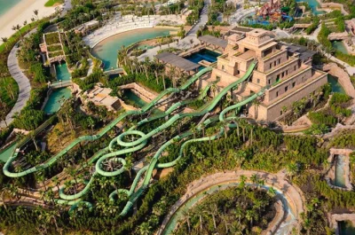 High-angle aerial perspective of the Mayan-themed water slide tower and twisting green water tubes at Aquaventure Waterpark on Palm Jumeirah.