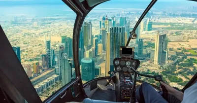 A man enjoys a helicopter tour, looking out at the expansive cityscape of Dubai from the cockpit.