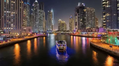 Illuminated luxury dhow cruise sailing across the Dubai Marina canal at night surrounded by glowing skyscrapers.