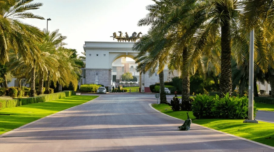 Grand entrance gate of Zabeel Palace featuring bronze running horse statues framed by manicured lawns and palm trees.